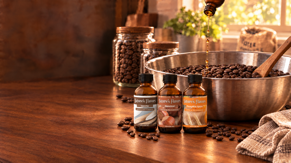 Vanilla, Hazelnut and Pumpkin Spice Coffee and Tea Flavoring 2 oz bottles beside a bowl of dry roasted coffee beans as flavoring pours in.