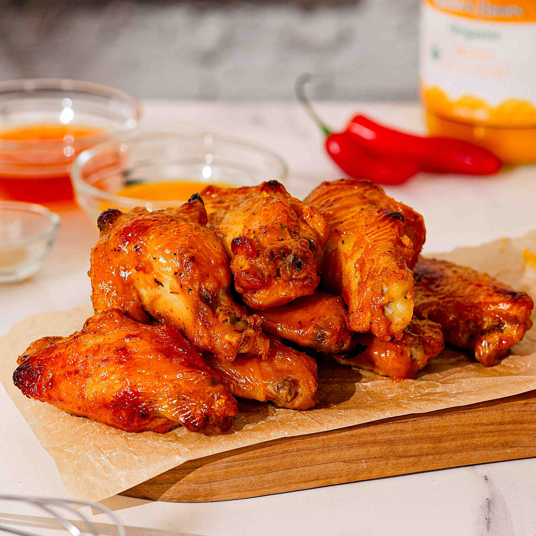 A wooden cutting board topped with juicy chicken wings, perfect for a meal or gathering.