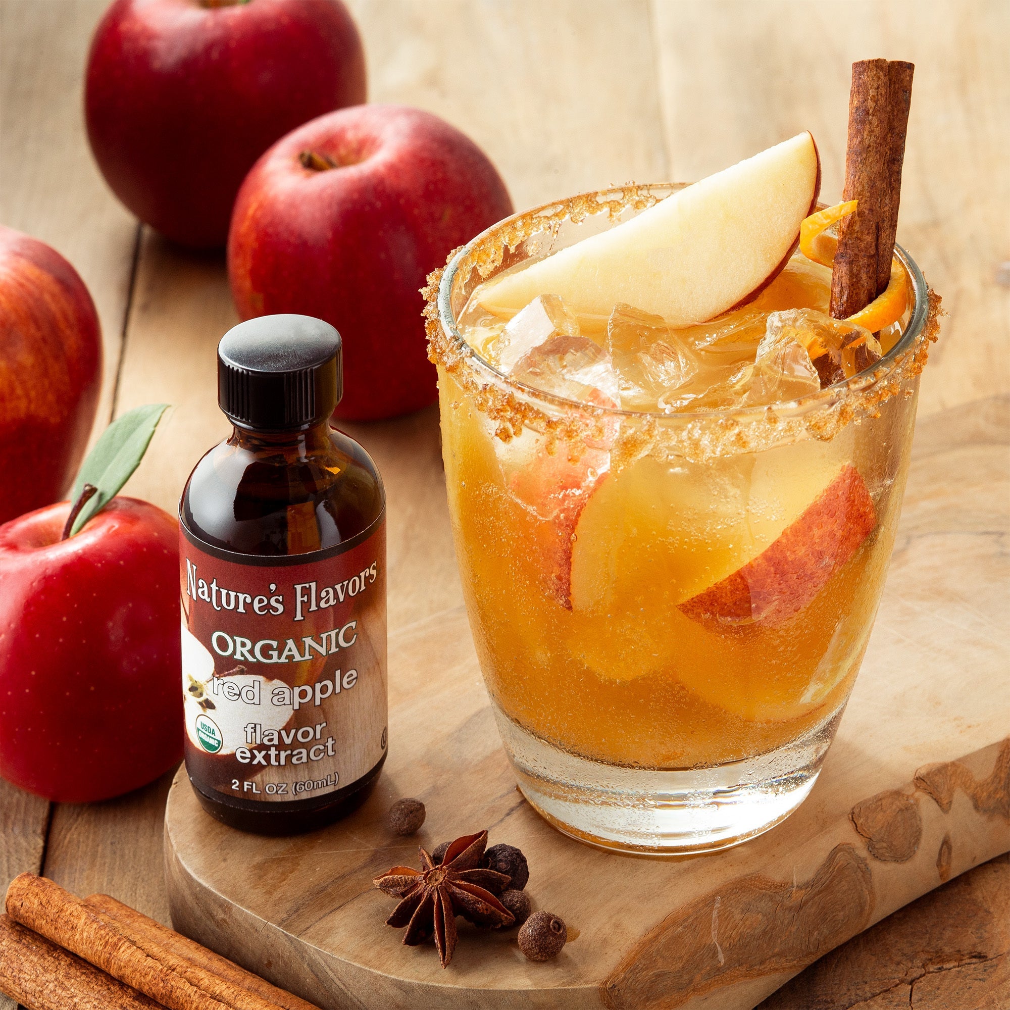 A refreshing glass of apple cider with cinnamon and a bright red apple resting on a rustic cutting board, flavored with nature's flavors organic apple cider flavor extract.