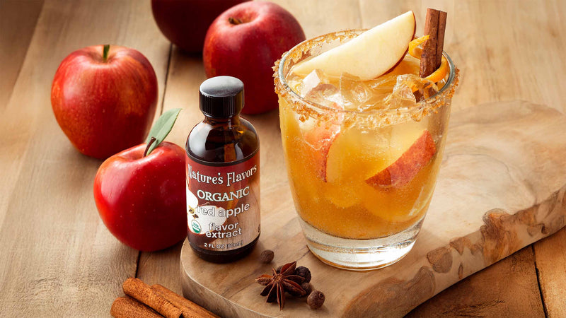 A refreshing glass of apple cider with cinnamon and a bright red apple resting on a rustic cutting board, flavored with nature's flavors organic apple cider flavor extract.