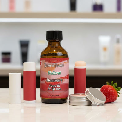 Bottle of Nature's Flavors Natural Strawberry Flavor Oil for Lip Balm on a counter with lip balm sticks and a strawberry.