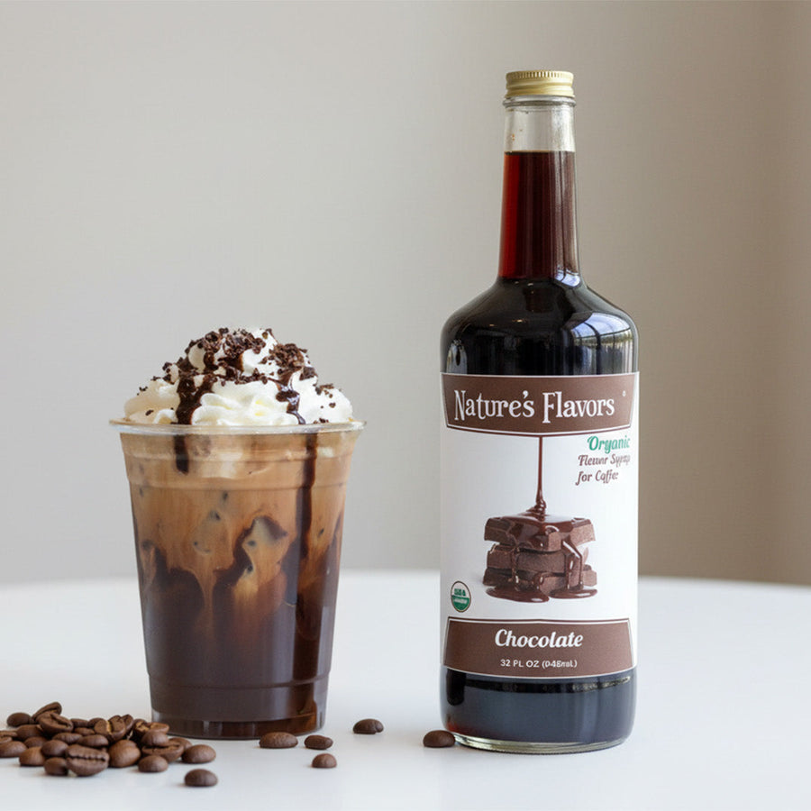 Bottle of Nature's Flavors chocolate syrup with a coffee drink and coffee beans on a white surface.