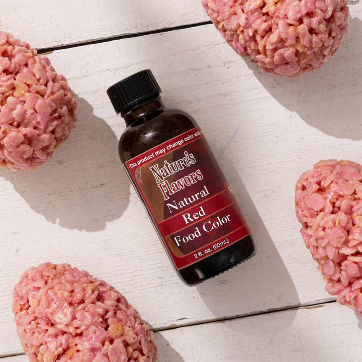 Bottle of Nature's Flavors Natural Red Food Color with pink rice krispie treats on a light background