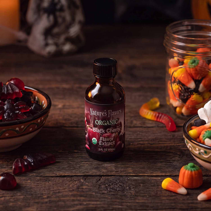 Bottle labeled, "Organic Black Cherry Flavor Extract" next to Halloween themed candy. 
