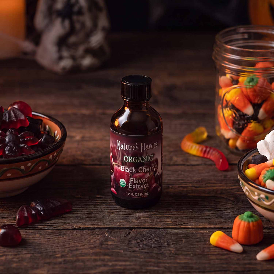 Bottle labeled, "Organic Black Cherry Flavor Extract" next to Halloween themed candy. 