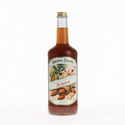 A bottle of Nature's Flavors Almond Syrup with a gold cap, filled with amber liquid, and featuring a cream-colored label with illustrations of almonds, set against a plain white background.