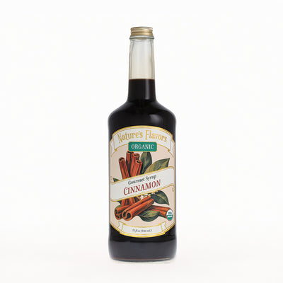 A bottle of Nature's Flavors Organic Gourmet Syrup, Cinnamon flavor, in a clear glass bottle with a gold cap, set against a plain white background.