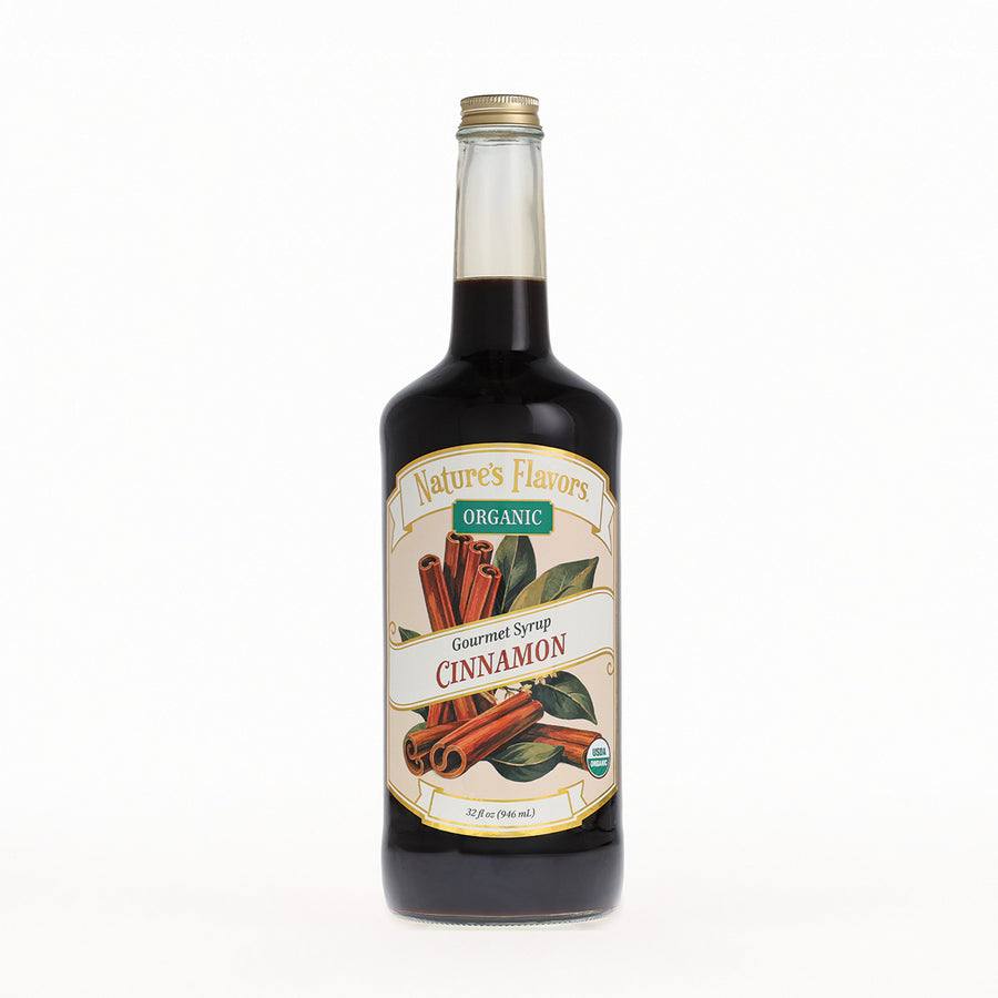 A bottle of Nature's Flavors Organic Gourmet Syrup, Cinnamon flavor, in a clear glass bottle with a gold cap, set against a plain white background.