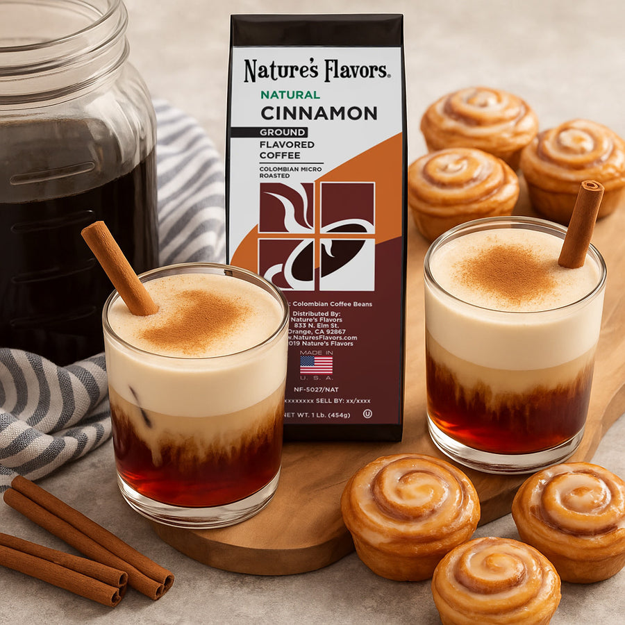 Two glasses of a layered drink with cinnamon on a wooden board, accompanied by Nature's Flavors cinnamon coffee package and cinnamon rolls.