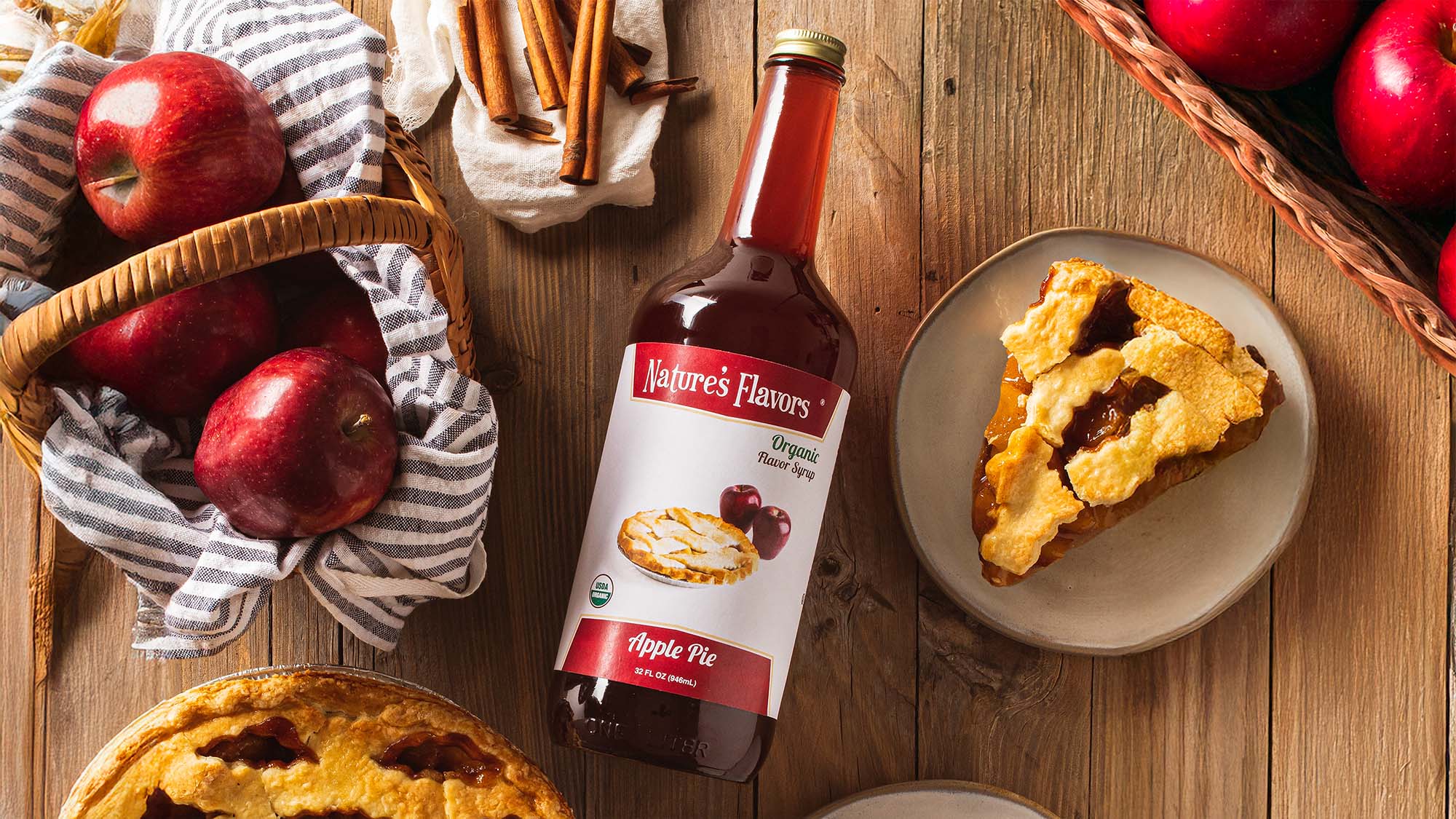Nature's Flavors Apple Pie flavor syrup bottle with apple pie slices and apples on a wooden table.