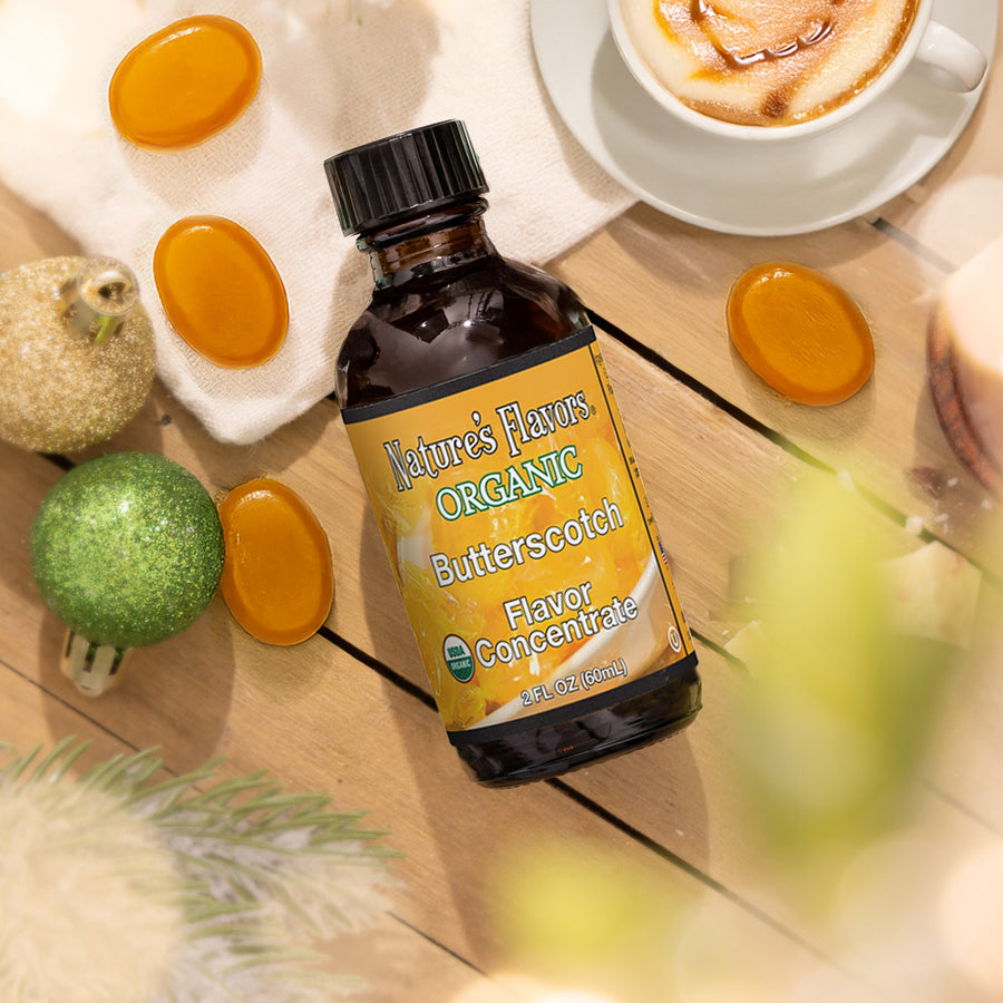 Bottle of Nature's Flavors Organic Butterscotch Flavor Concentrate on a wooden surface with decorative items.
