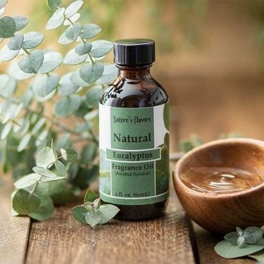 Bottle of Nature's Flavors Eucalyptus Fragrance Oil with eucalyptus leaves and a wooden bowl in the background.