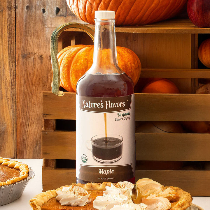 Bottle of Nature's Flavors maple flavored syrup with pumpkins and pies in the background