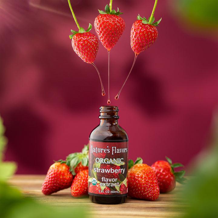 3 floating strawberries all dripping a red fluid into a bottle labeled, "Organic Strawberry Flavor Extract".