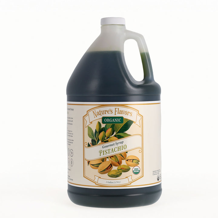 A one-gallon jug of Nature's Flavors Organic Gourmet Pistachio Syrup, filled with a dark green liquid, featuring a white cap and a detailed cream-colored label with illustrations of green pistachios.