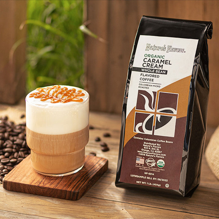 Black bag labeled, "Caramel Cream Whole Bean Flavored Coffee" next to a cup of iced coffee with foam and drizzle. 