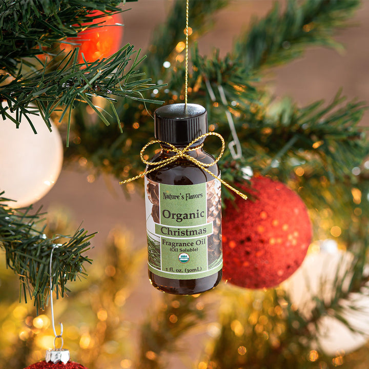 bottle labeled, "organic Christmas Fragrance Oil" hanging from a tree as an ornament. 