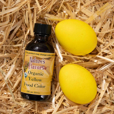 Nature's Flavors Organic Yellow Food Color bottle with two yellow eggs on straw