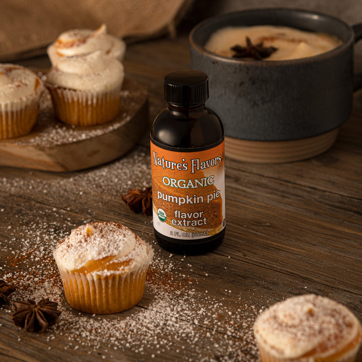 bottle labeled, "Organic pumpkin pie flavor extract" next to cupcakes and a cup of coffee. 
