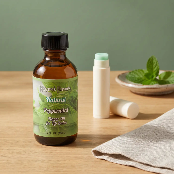Nature's Flavors Peppermint Flavor Oil for Lip Balm, 2 oz bottle with peppermint and an open unbranded lip balm tube.