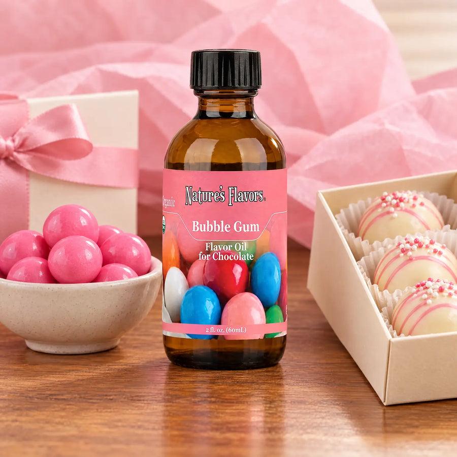 Nature's Flavors Organic Bubble Gum Flavor Oil For Chocolate, 2-ounce bottle, with pink gumballs and boxed white chocolate bonbons.