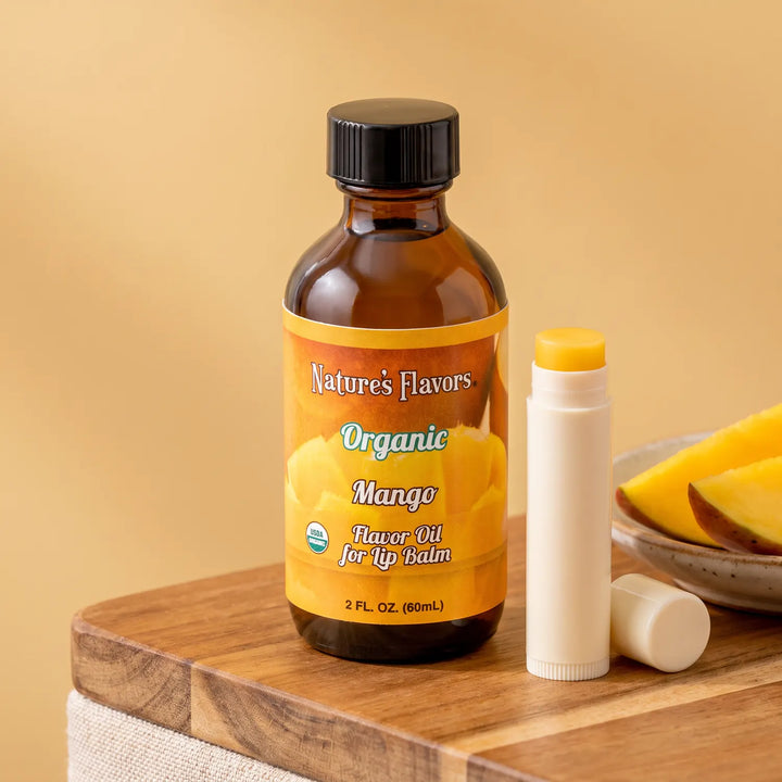 Nature's Flavors Organic Mango Flavor Oil for Lip Balm, 2 oz bottle with mango and an open unbranded lip balm tube.