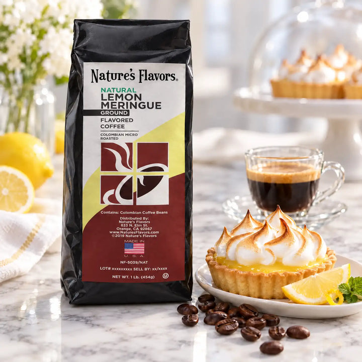 Nature’s Flavors Lemon Meringue Flavored Coffee Beans, 1 lb. Ground, in a black labeled bag beside lemon meringue tart, whole roasted coffee beans and a filled coffee drink in a bright coffee scene.