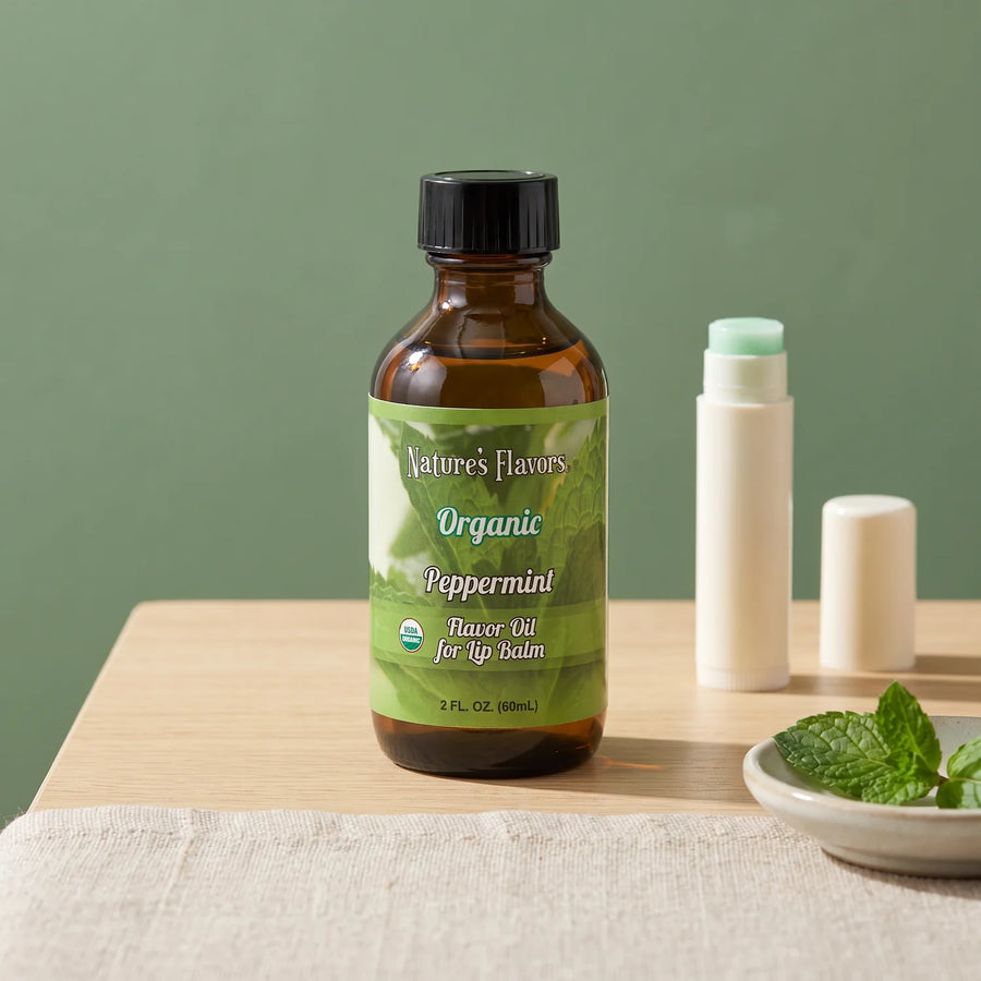 Nature's Flavors Organic Peppermint Flavor Oil for Lip Balm, 2 oz bottle with peppermint and an open unbranded lip balm tube.