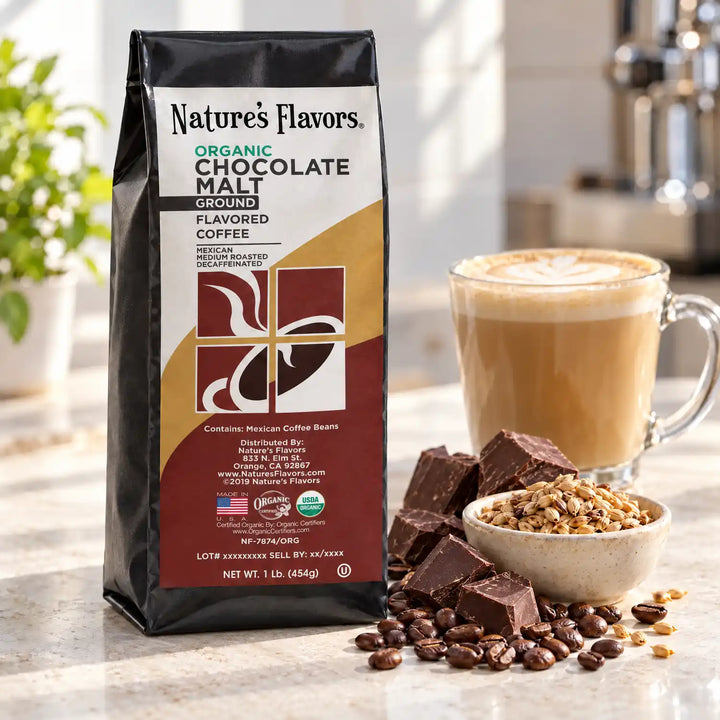 Nature’s Flavors Organic Decaf Chocolate Malt Flavored Coffee Beans, 1 lb. Ground, in a black labeled bag beside chocolate and malted barley, whole roasted coffee beans and a filled coffee drink in a bright coffee scene.