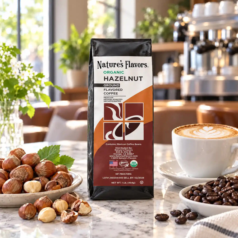 Nature’s Flavors Organic Decaf Hazelnut Flavored Coffee Beans, 1 lb. Ground, in a black labeled bag with whole roasted coffee beans and a filled coffee drink in the retained bright scene.