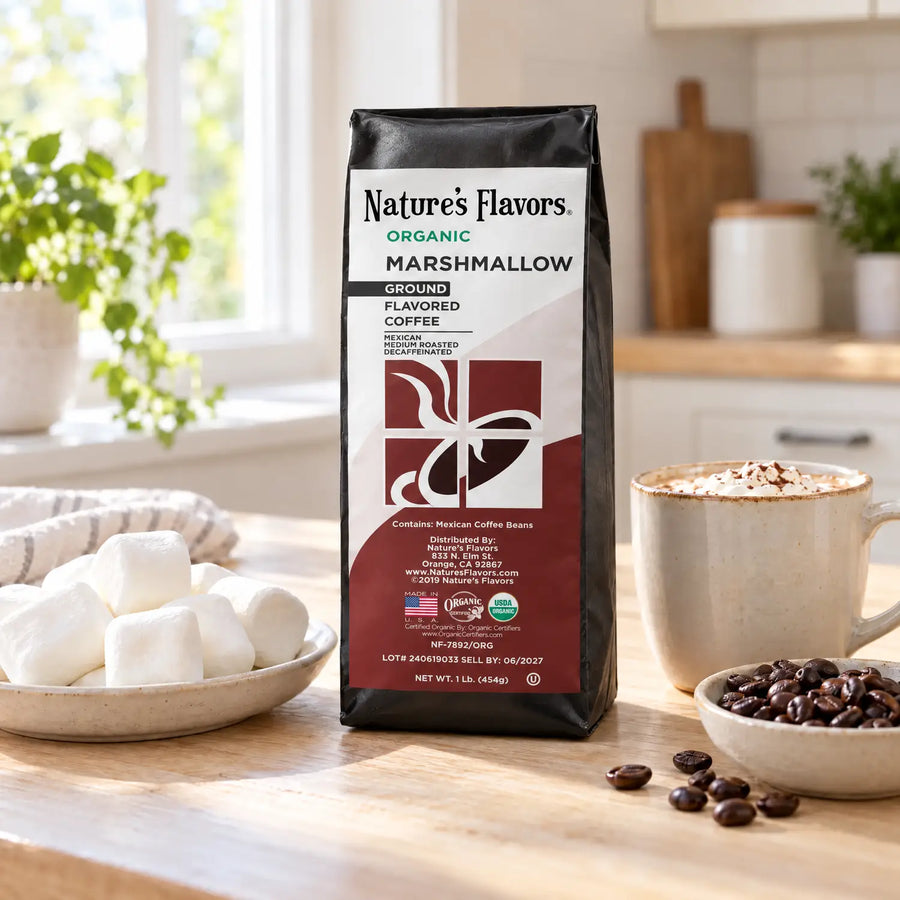 Nature’s Flavors Organic Decaf Marshmallow Flavored Coffee Beans, 1 lb. Ground, in a black labeled bag with whole roasted coffee beans and a filled coffee drink in the retained bright scene.