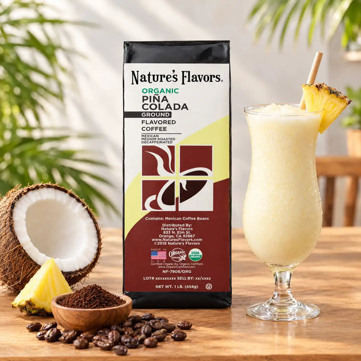 Nature’s Flavors Organic Decaf Pina Colada Flavored Coffee Beans, 1 lb. Ground, in a bright tropical café beside coconut and pineapple on the left, a filled Piña Colada on the right, and roasted beans with contained grounds.