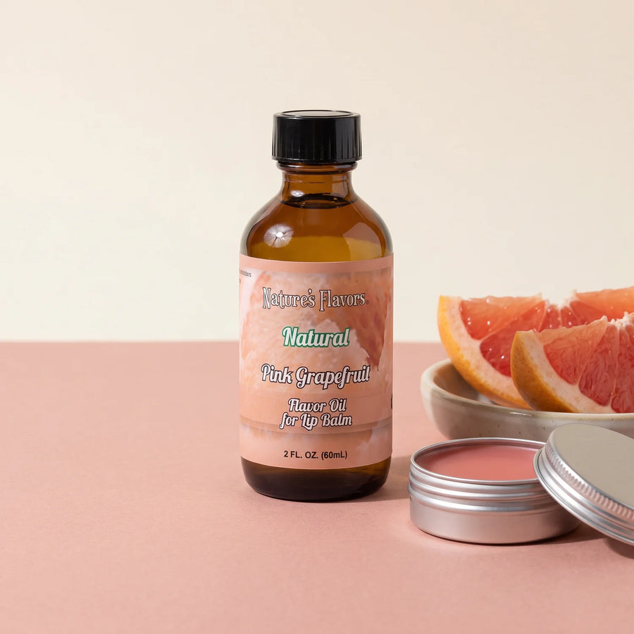 Nature's Flavors Pink Grapefruit Blend Flavor Oil for Lip Balm, 2 oz bottle with grapefruit and an open unbranded lip balm tin.