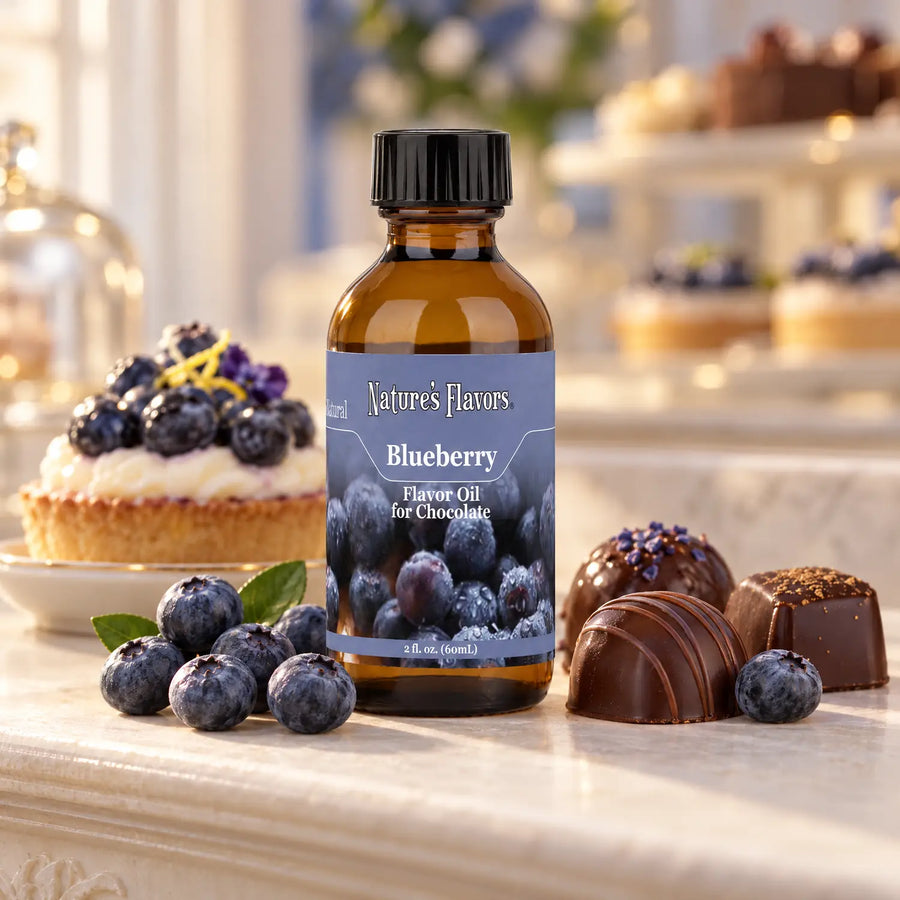 Nature's Flavors Blueberry Flavor Oil for Chocolate bottle beside blueberries, a blueberry pastry, and dark chocolate truffles at a patisserie.