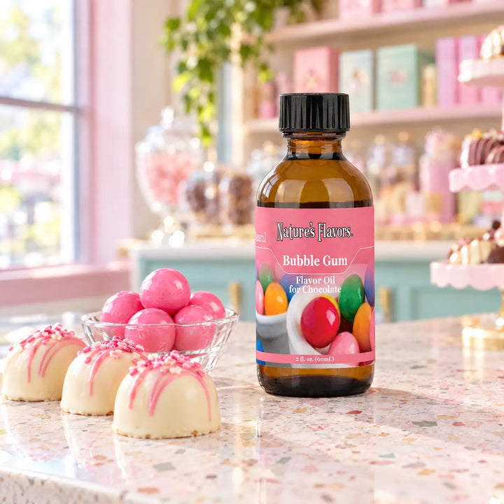 Nature's Flavors Bubble Gum Flavor Oil for Chocolate, 2-ounce bottle, with pink gumballs and white chocolate bonbons in a chocolate shop.
