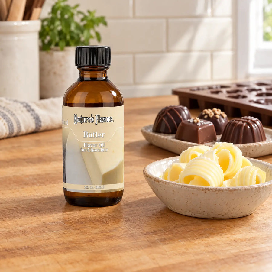 Nature's Flavors Butter Flavor Oil for Chocolate, 2-ounce bottle, with butter curls and chocolate bonbons in a working kitchen.