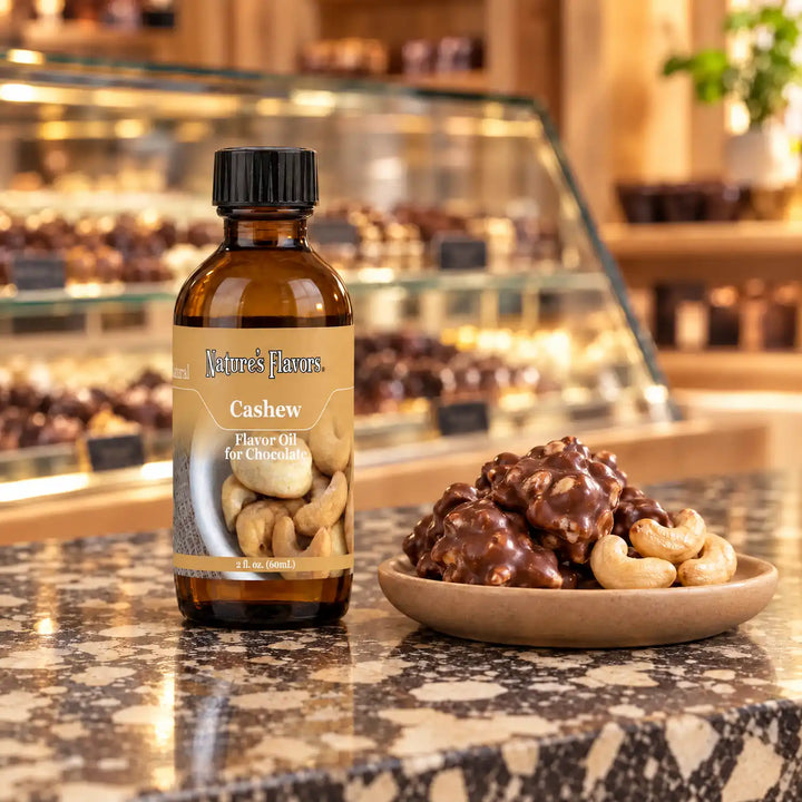 Nature's Flavors Cashew Flavor Oil for Chocolate, 2-ounce bottle, with cashews and chocolate clusters in a chocolate shop.