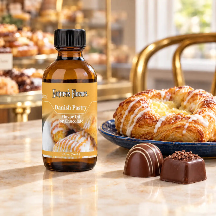 Nature's Flavors Danish Pastry Flavor Oil for Chocolate, 2-ounce bottle, with a Danish pastry and chocolate bonbons at a patisserie.