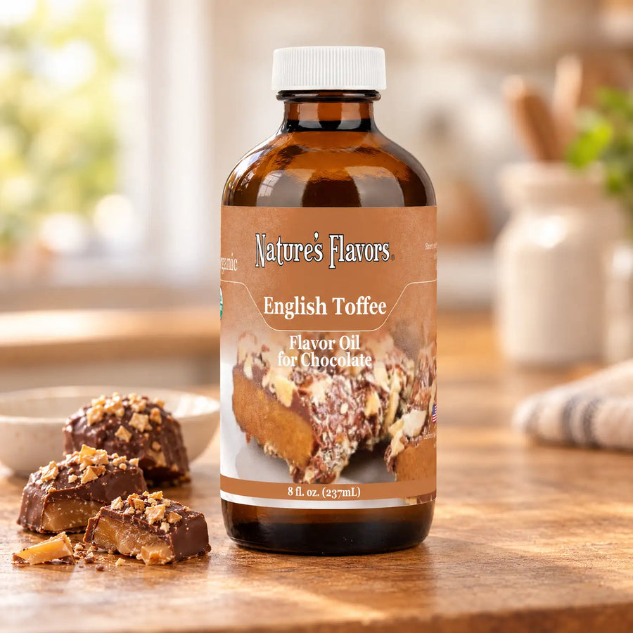 An eight-ounce bottle of Nature's Flavors English Toffee Flavor Oil for Chocolate with a white cap beside chocolate-covered toffee pieces.