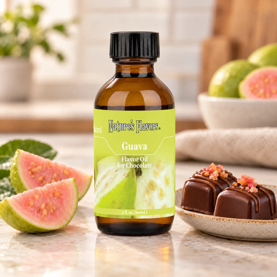 Nature's Flavors Guava Flavor Oil for Chocolate bottle beside pink guava wedges and chocolate bonbons on a small dish.