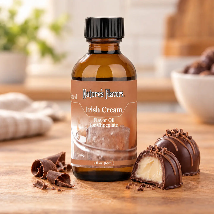 Nature's Flavors Irish Cream Flavor Oil for Chocolate bottle beside chocolate curls and truffles, including one with a pale cream filling.