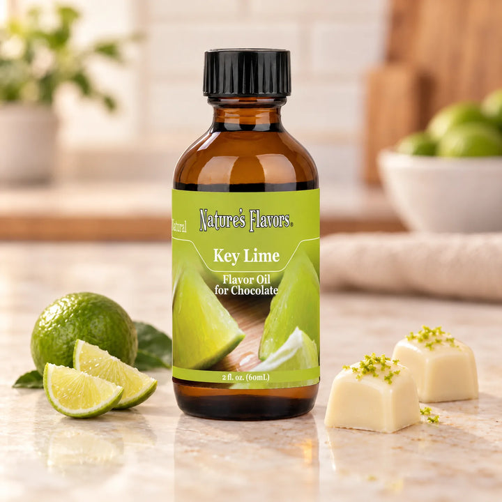 Nature's Flavors Key Lime Flavor Oil for Chocolate bottle beside a small whole lime, lime wedges, and white chocolate bonbons.
