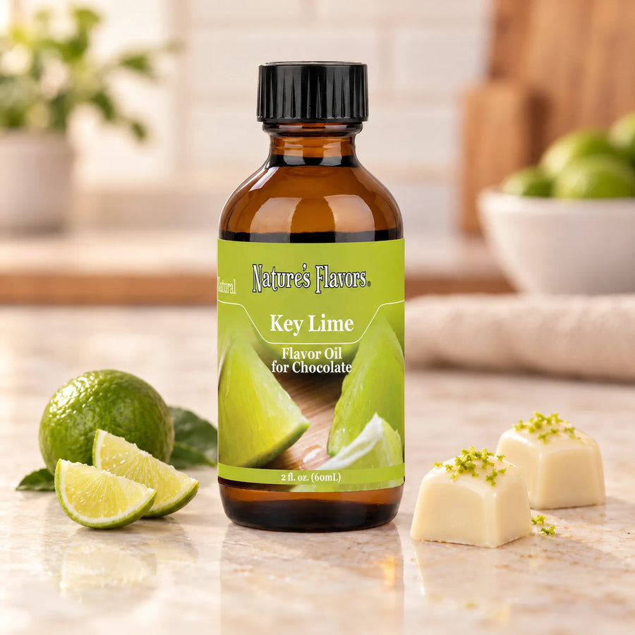 Nature's Flavors Key Lime Flavor Oil for Chocolate bottle beside a small whole lime, lime wedges, and white chocolate bonbons.