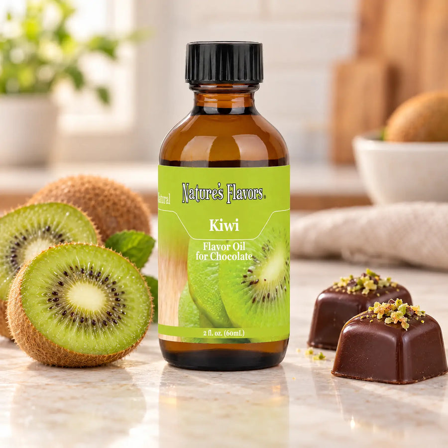 Nature's Flavors Kiwi Flavor Oil for Chocolate bottle beside cut kiwi fruit and dark chocolate bonbons on a light countertop.