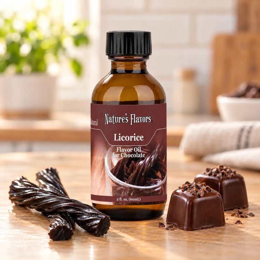 Nature's Flavors Licorice Flavor Oil for Chocolate bottle beside black licorice twists and dark chocolate bonbons on a wooden countertop.