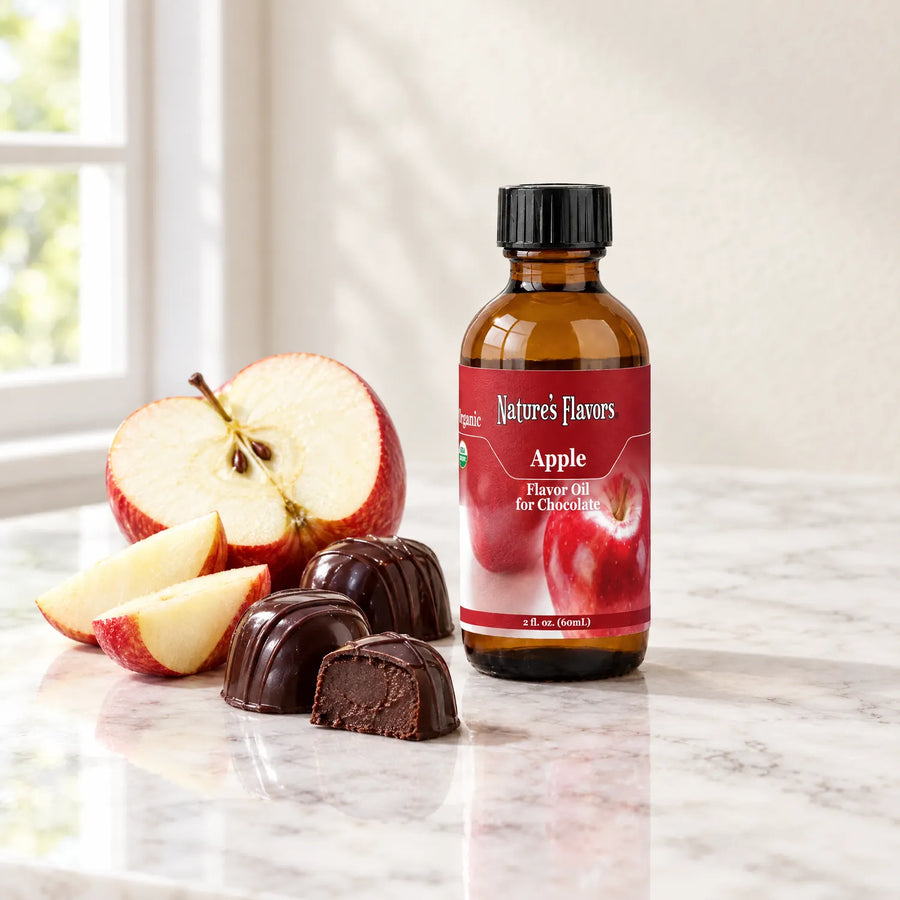 Nature's Flavors Organic Apple Flavor Oil For Chocolate, 2-ounce bottle, with red apple wedges and chocolate bonbons on marble.