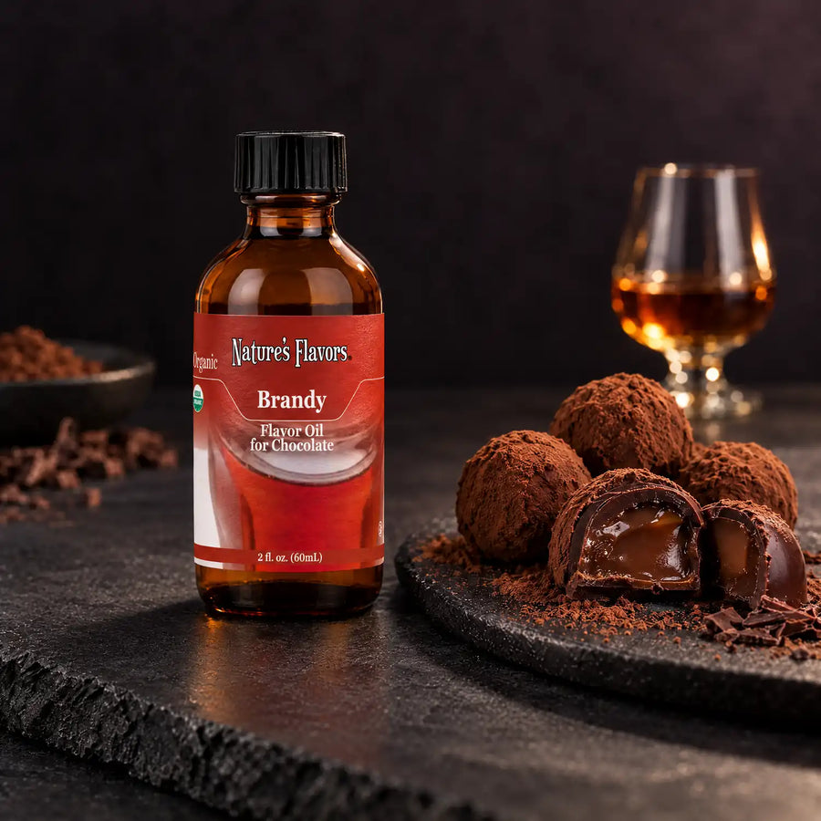 Nature's Flavors Organic Brandy Flavor Oil For Chocolate, 2-ounce bottle, with brandy and filled chocolate bonbons on dark slate.