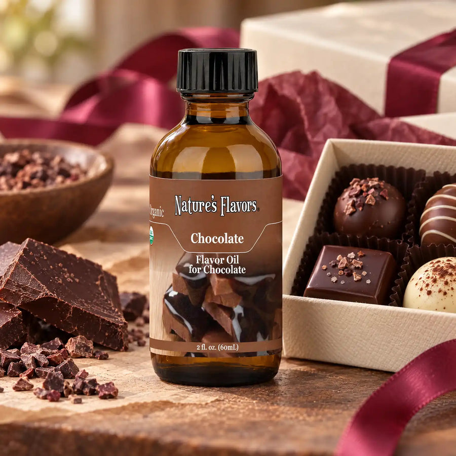 Nature's Flavors Organic Chocolate Flavor Oil for Chocolate bottle beside a chocolate gift box, cocoa nibs, and dark chocolate pieces.