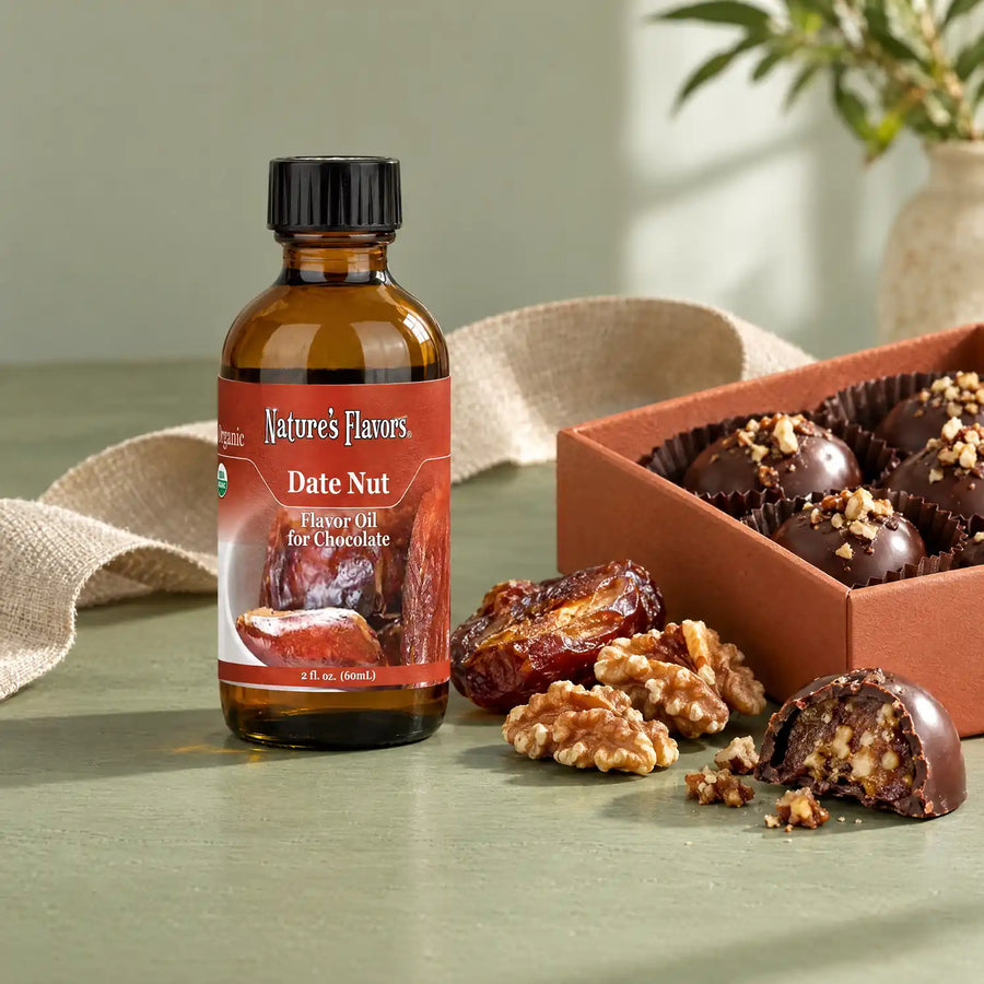 Nature's Flavors Organic Date Nut Flavor Oil For Chocolate, 2-ounce bottle, with dates, walnuts and boxed chocolates on a gift table.