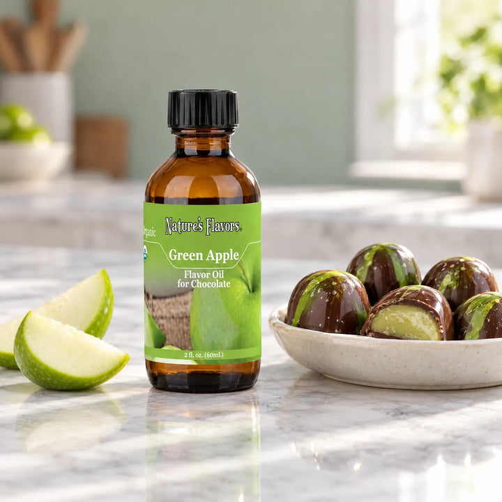 Nature's Flavors Organic Green Apple Flavor Oil For Chocolate, 2-ounce bottle, with green apple wedges and chocolate bonbons on light marble.